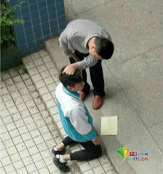 張姓老師手拿帶插線板的電線，另一隻手揪住跪在地上的學生的頭髮。